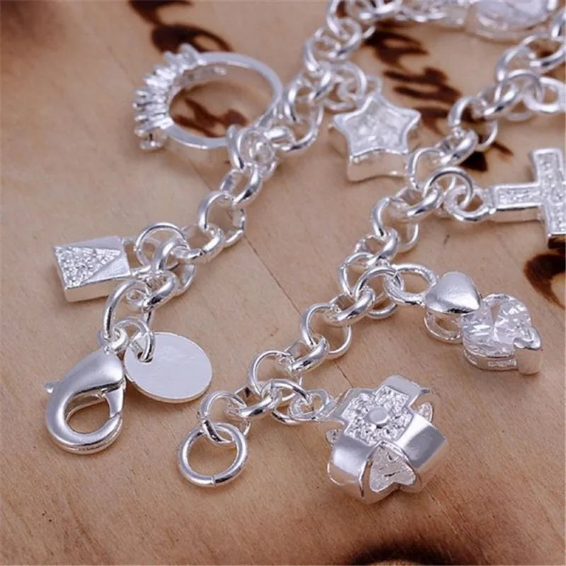 A close-up of a silver geometric charm bracelet featuring various charms including stars, crosses, and hearts.
