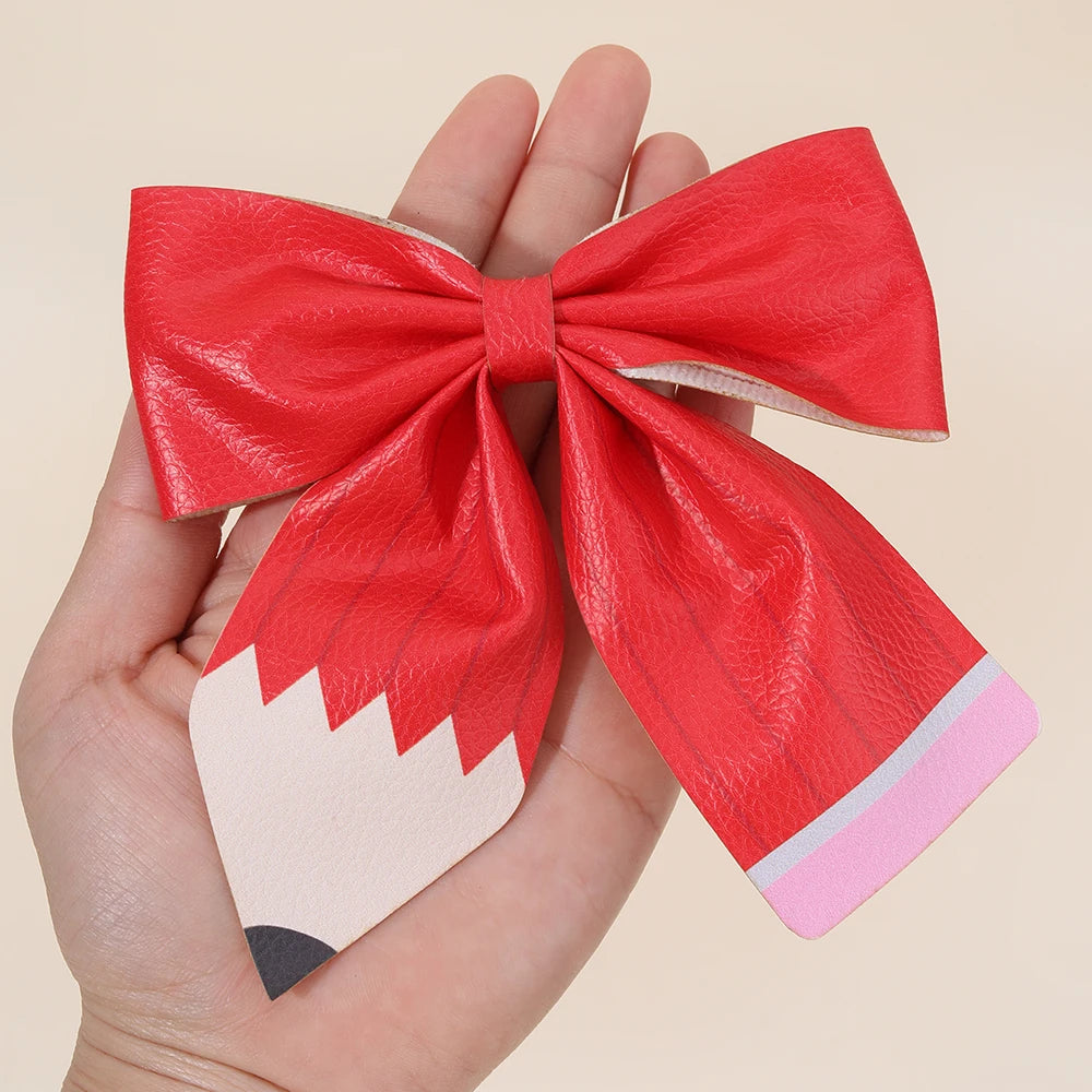 A red ribbon bow shaped like a pencil is held in a hand.