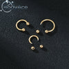 A set of gold-colored titanium steel nose rings with CZ crystals displayed on a dark surface.