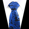 A close-up of an elegant blue and black floral paisley silk necktie worn with a white shirt.