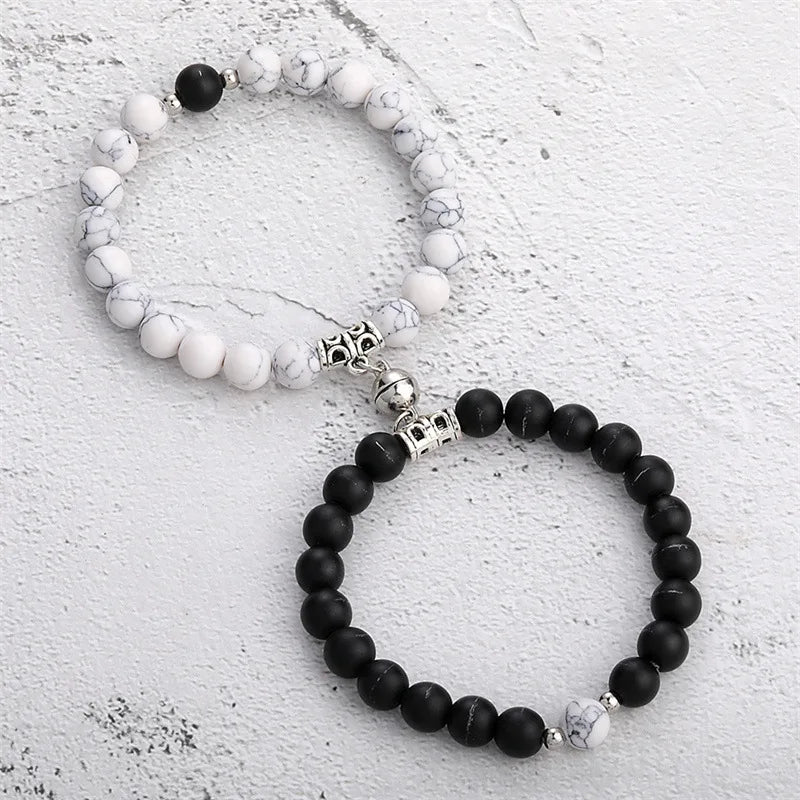 A pair of natural stone heart couple bracelets featuring white and black marbled beads.