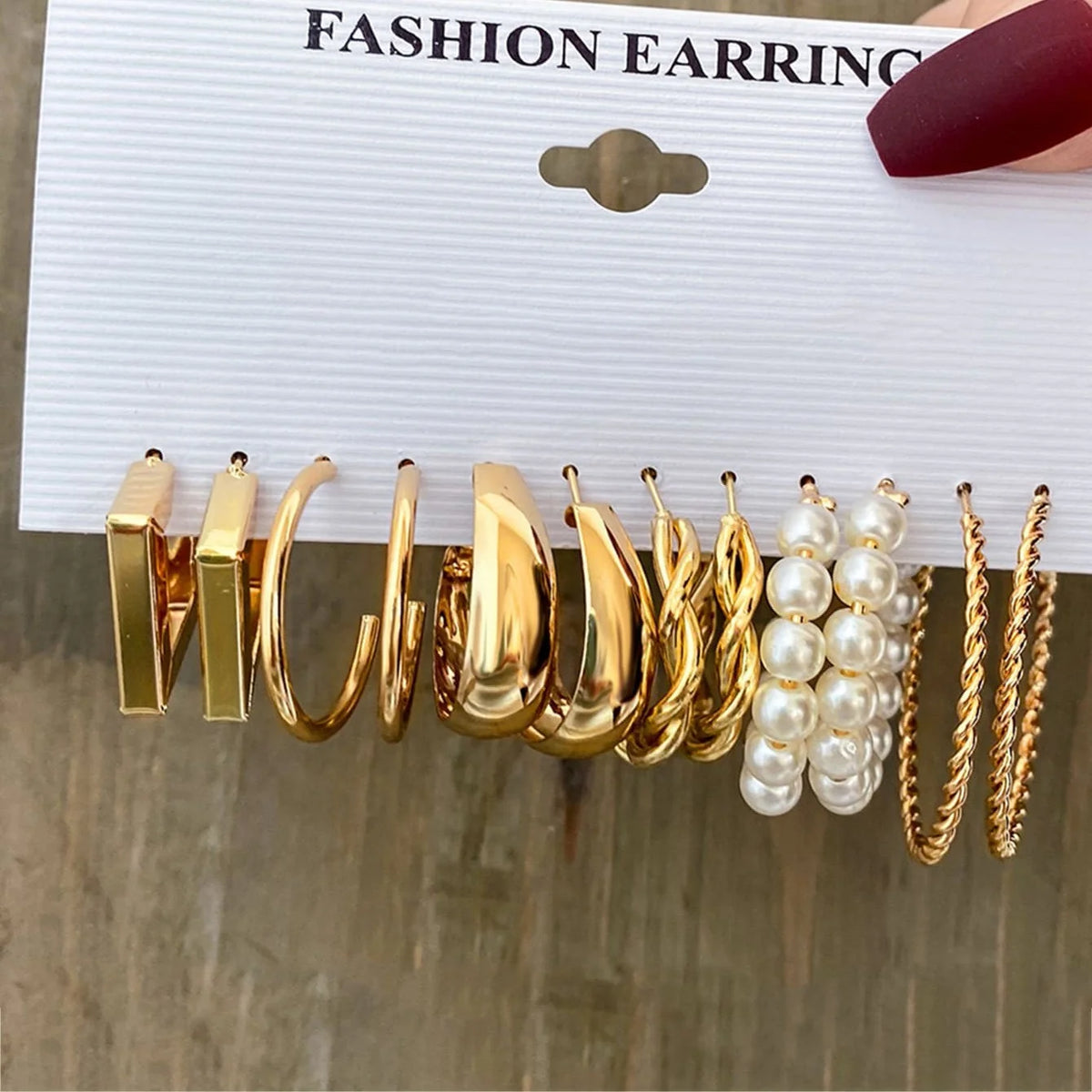 Un ensemble d'boucles d'oreilles géométriques dorées bohèmes et de perles présentées sur une carte blanche.
