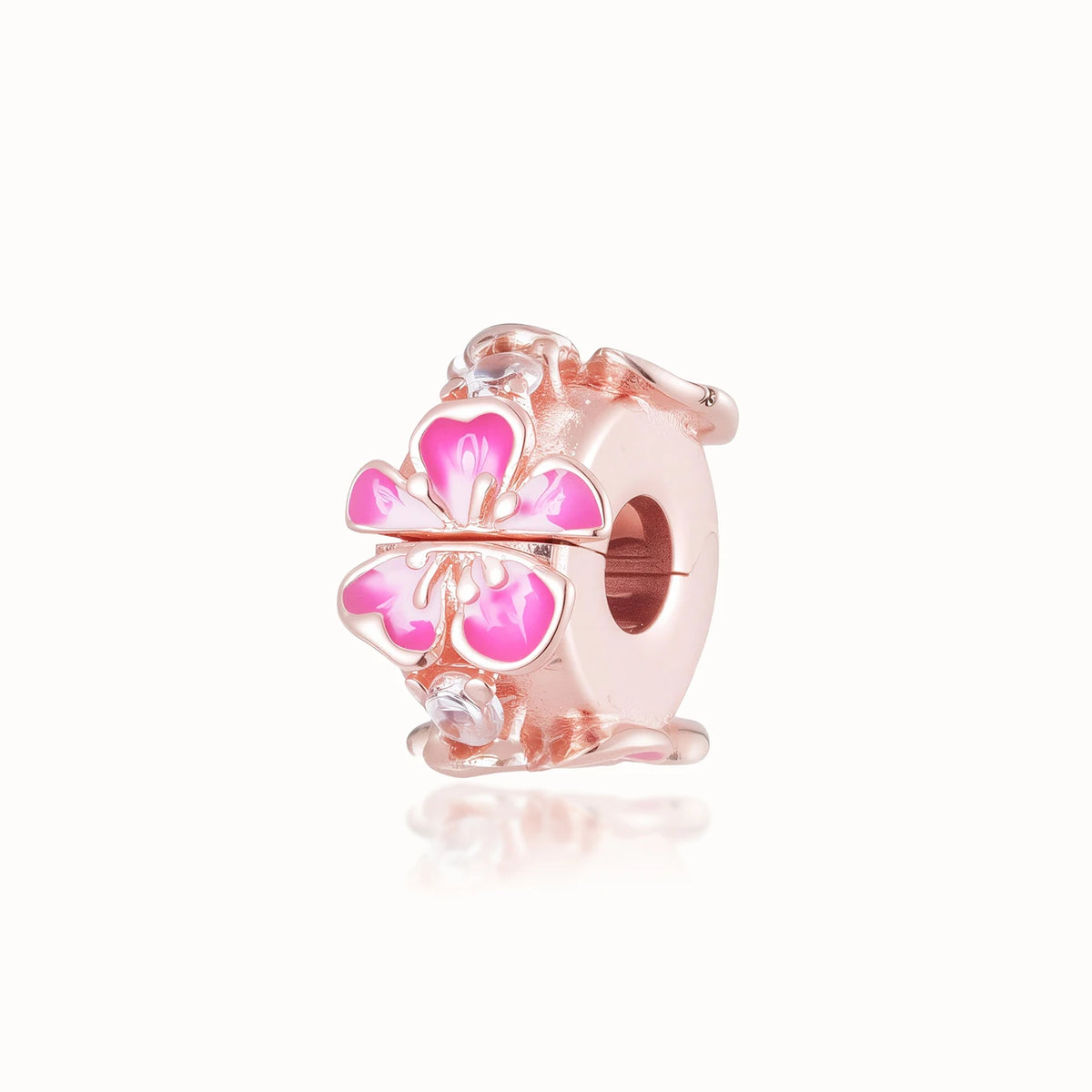Una pequeña cuenta de adorno rosa con un diseño floral y acentos rosa y blanco.