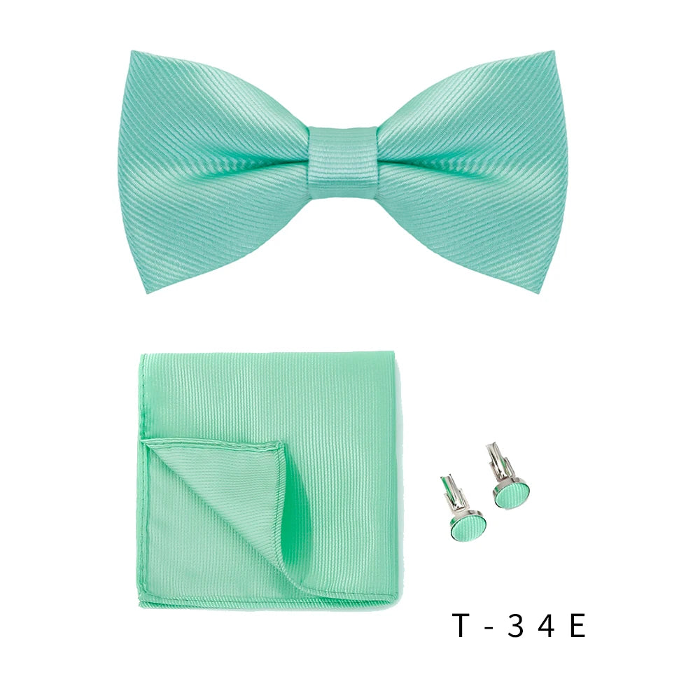 A mint green bow tie and cufflink set displayed on a white background.