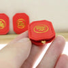 A hand holds a small red charm shaped like a turtle, used for longevity and financial stability.