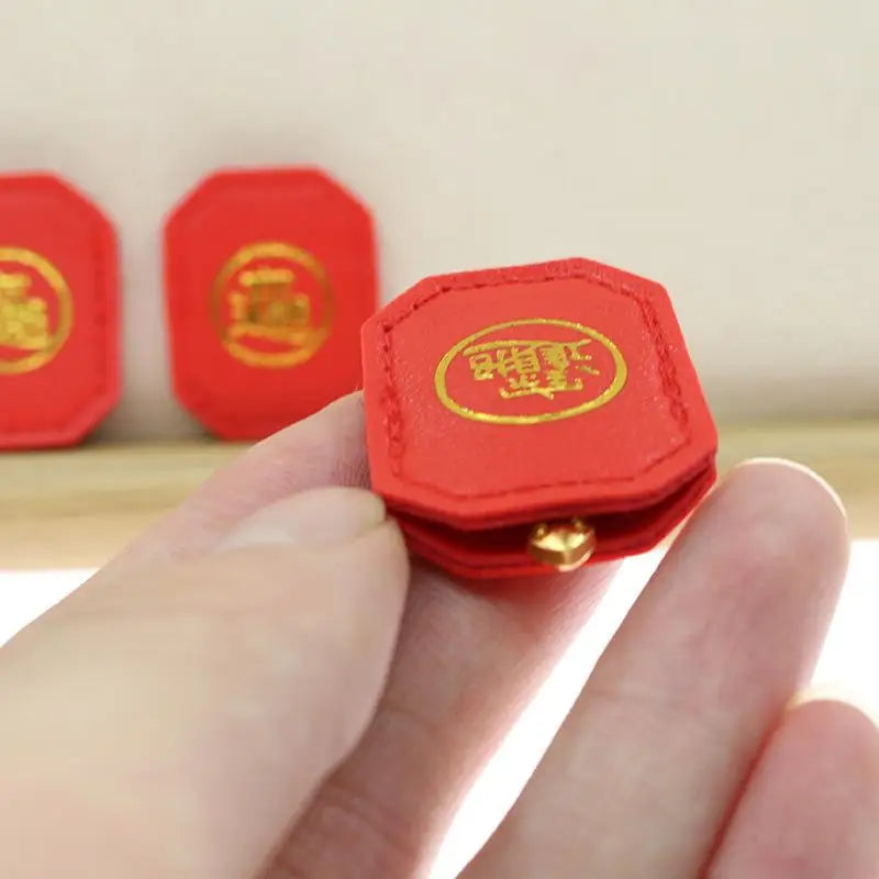 A hand holds a small red charm shaped like a turtle, used for longevity and financial stability.