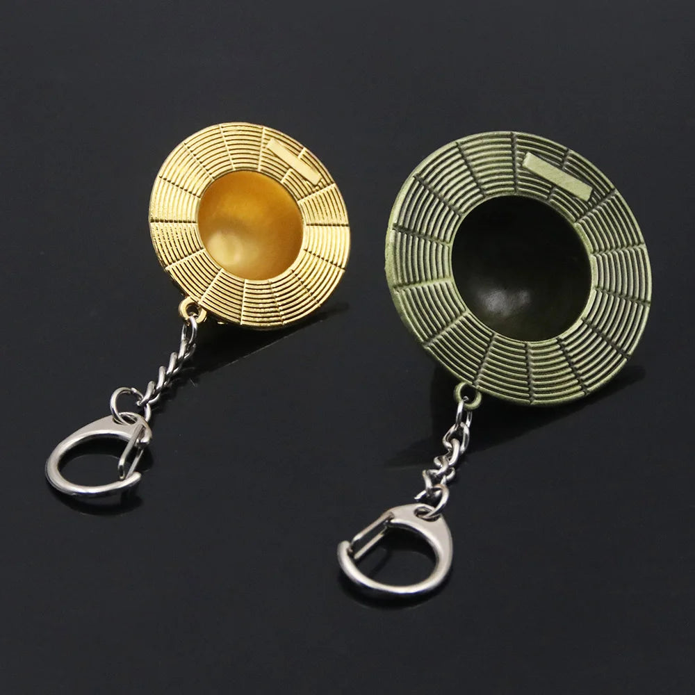 A gold-toned metal keychain featuring a straw hat design with a green and gold texture.