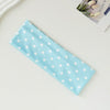 Light blue fabric hairband with white polka dots lying on a light surface.