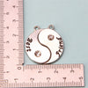 Collar de amistad plateado con dos colgantes estilo yin-yang marcados Best y Friend, medido con una regla.