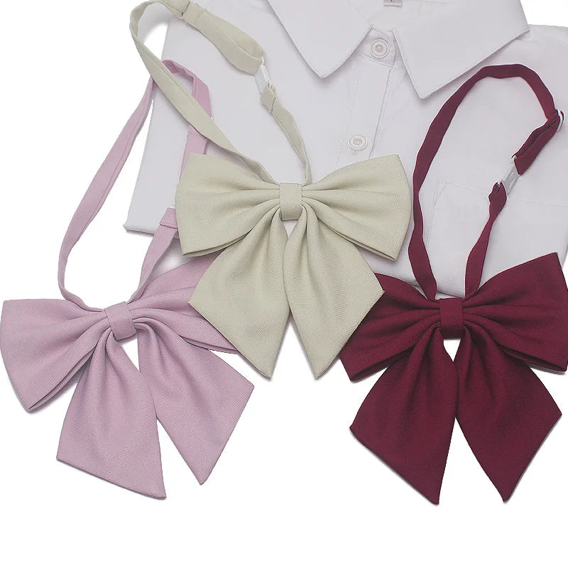 A set of three butterfly ribbon ties in pink, beige, and burgundy for students