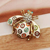 Broche dorée avec motif d'abeille et motifs circulaires iridescents et colorés sur les ailes