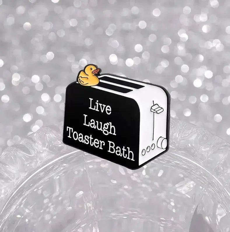 An enamel pin featuring a cartoon duck on a bread maker design.