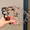 A hand holds a set of fashion acetate toothed headbands with various translucent and colored shades.