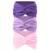 Ein Set aus drei rutschfesten Haarbänder in Lila, Lavendel und Pink, zu einem Schleifchen gebunden.