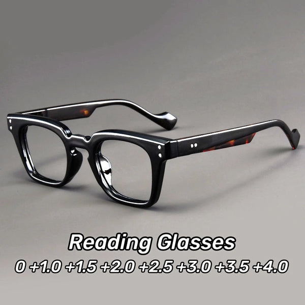 A pair of black reading glasses with dark lenses and thin frames displayed on a gray background.