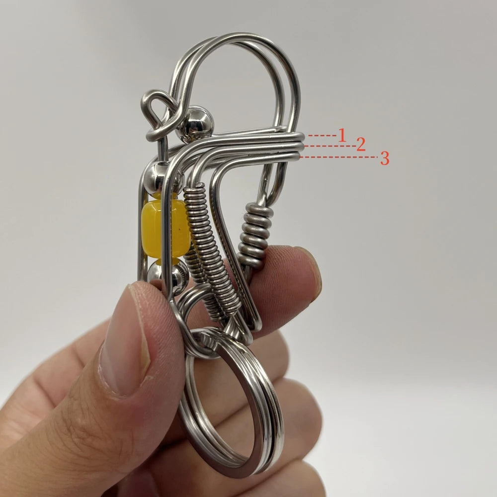 Clé mécanique en acier inoxydable avec ressort et perle jaune.