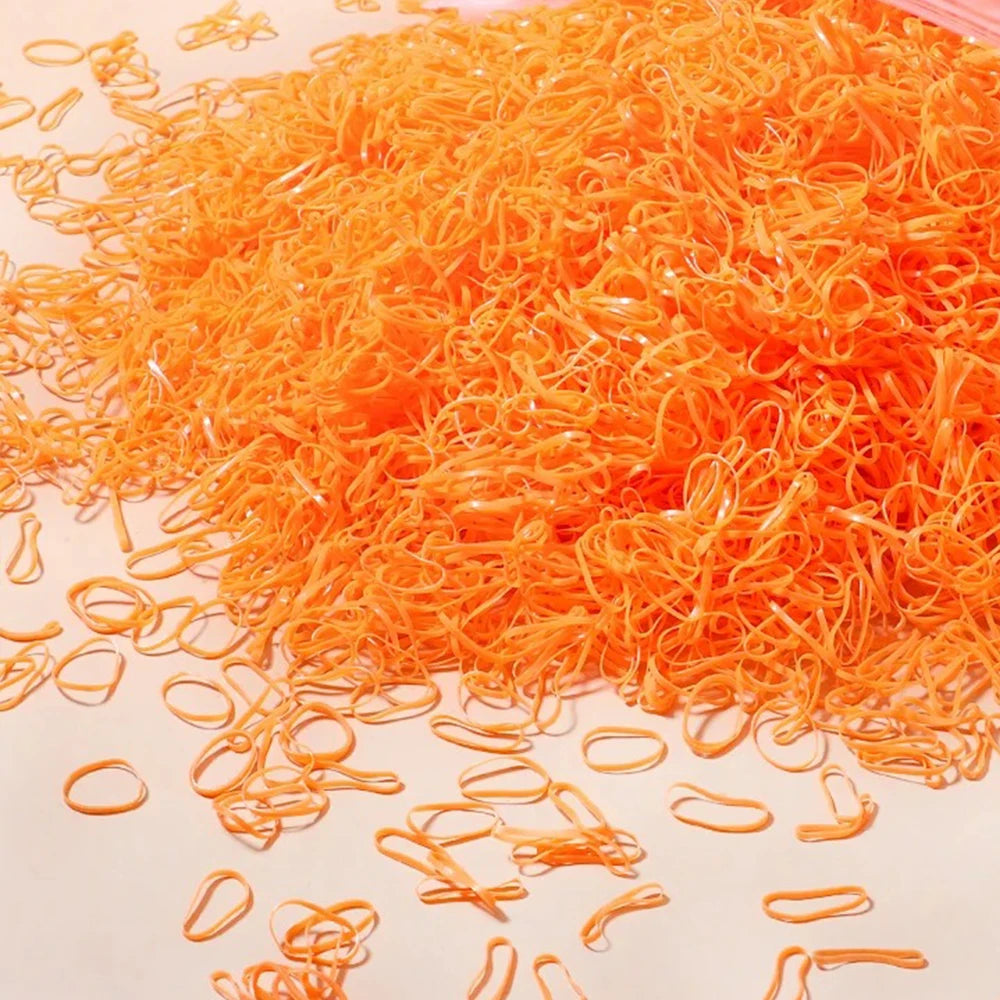 A pile of bright orange disposable rubber hair ties for kids scattered on a white surface.