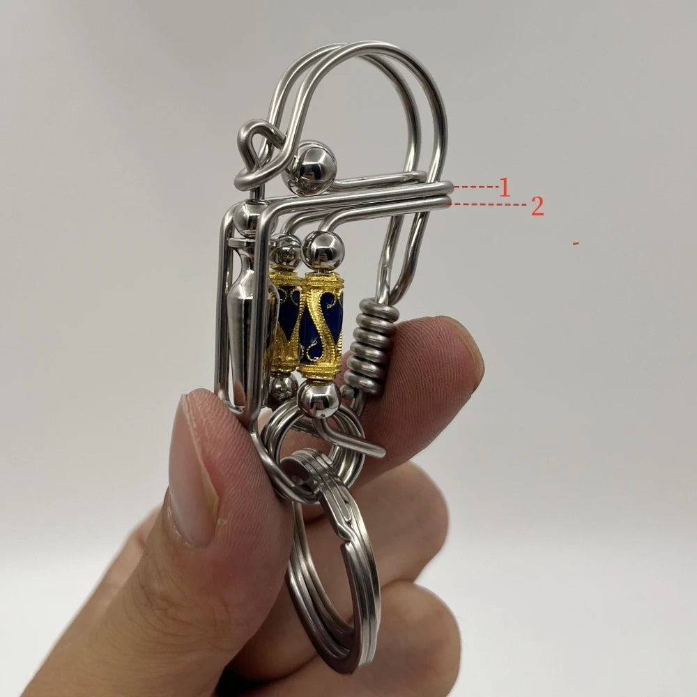 Porte-clés mécanique en acier inoxydable avec un élément décoratif doré et un anneau divisé.