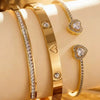 Ein Set aus drei 18K goldvergoldeten Edelstahlherzarmbändern mit Diamantbesatz auf hellem Hintergrund.
