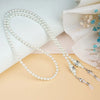 A delicate strand of white pearls used as a fashion beaded eyewear chain resting on a light background.