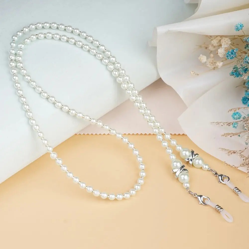 A delicate strand of white pearls used as a chain lanyard is displayed on a light background.