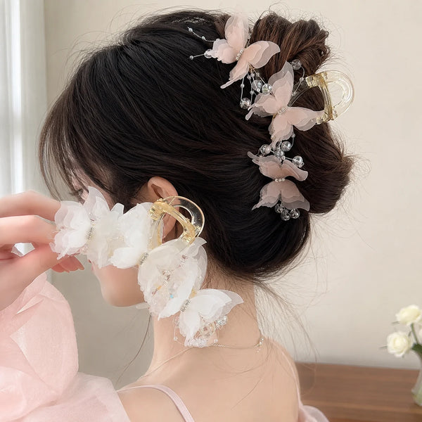 A woman's dark hair is styled with a pearl rhinestone butterfly hair claw clip featuring pink and clear accents.