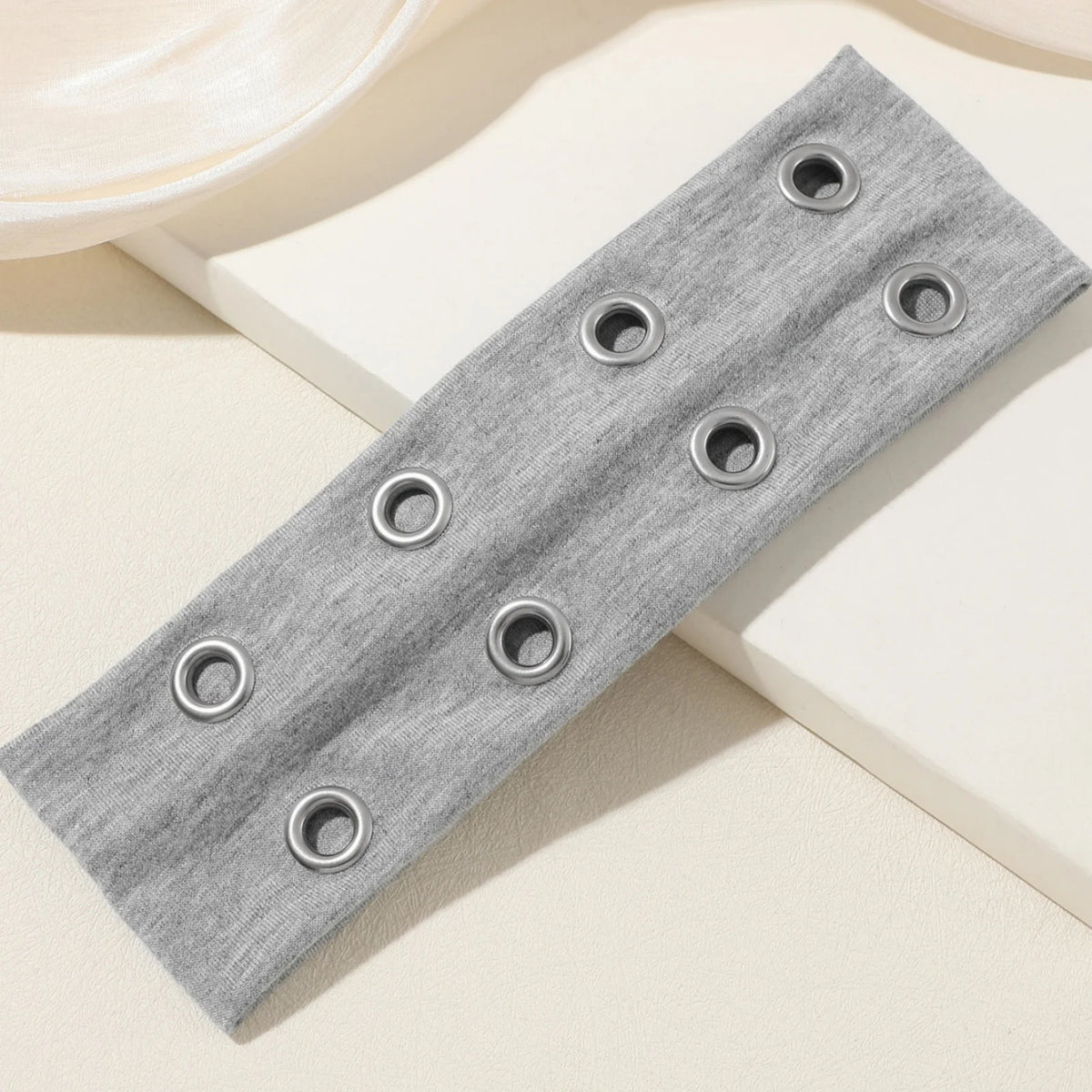 Gray fabric headband with multiple metal grommets for a punk style look