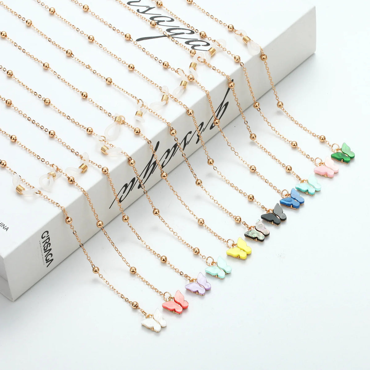 Gold-toned butterfly pendant necklace with delicate chain and small clear beads displayed on a white background.