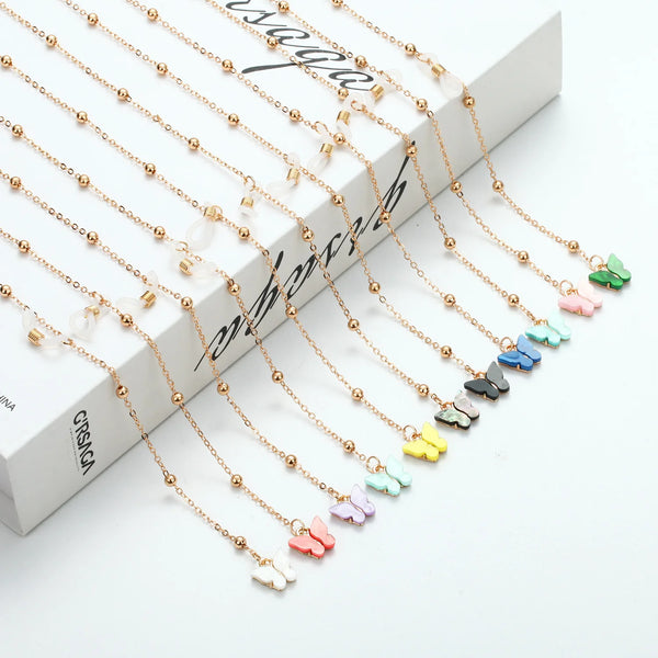 Gold-toned butterfly pendant necklace with delicate chain and small clear beads displayed on a white background.