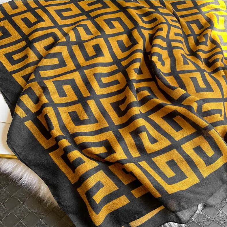 Gelb-schwarzer geometrisch gemusterter Luxus-Baumwoll-Pashmina-Schal, drapiert auf einer Oberfläche.