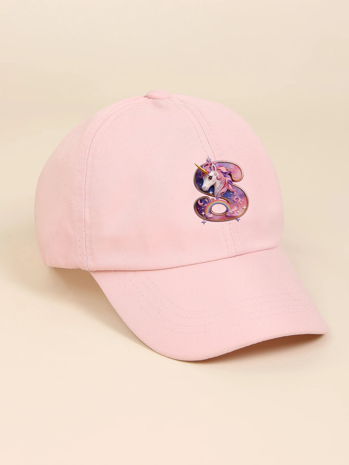 A pink baseball cap featuring a purple and pink rainbow unicorn design on the front.