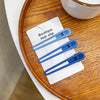 A set of five light blue vintage frosted geometry hair clips displayed on a white card on a wooden surface.