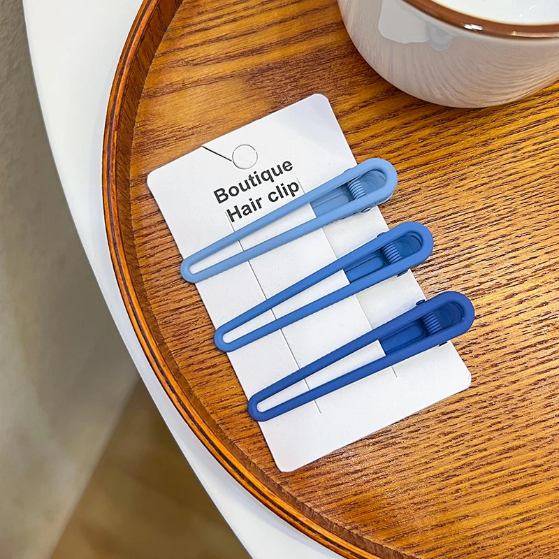 A set of five light blue vintage frosted geometry hair clips displayed on a white card on a wooden surface.