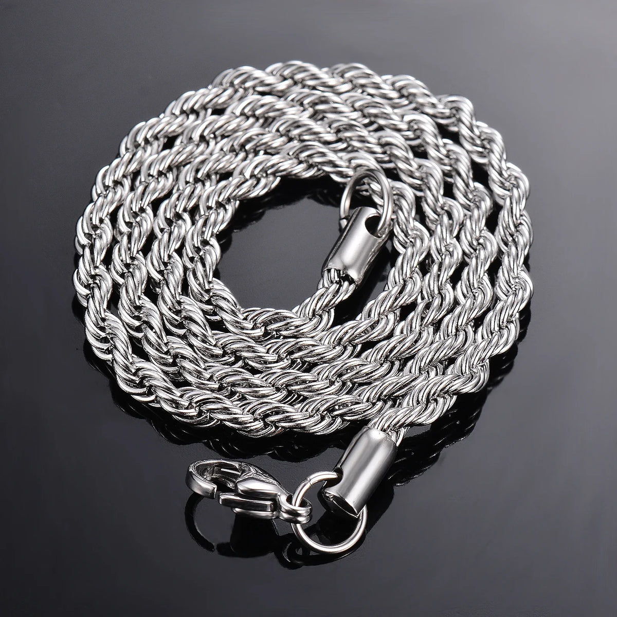 Collar de cadena de cuerda plateada con cierre y aro de salto sobre una superficie oscura y reflectante.