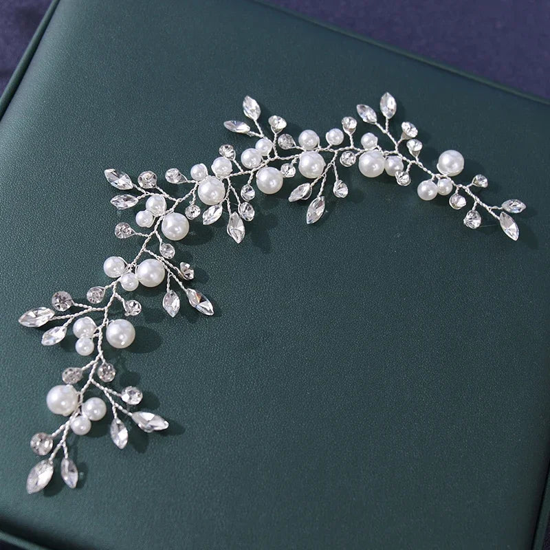 An elegant pearl bridal hairband featuring delicate white pearls and clear crystals on a dark green background.