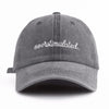 A gray washed baseball cap with white embroidered text that reads overstimulated