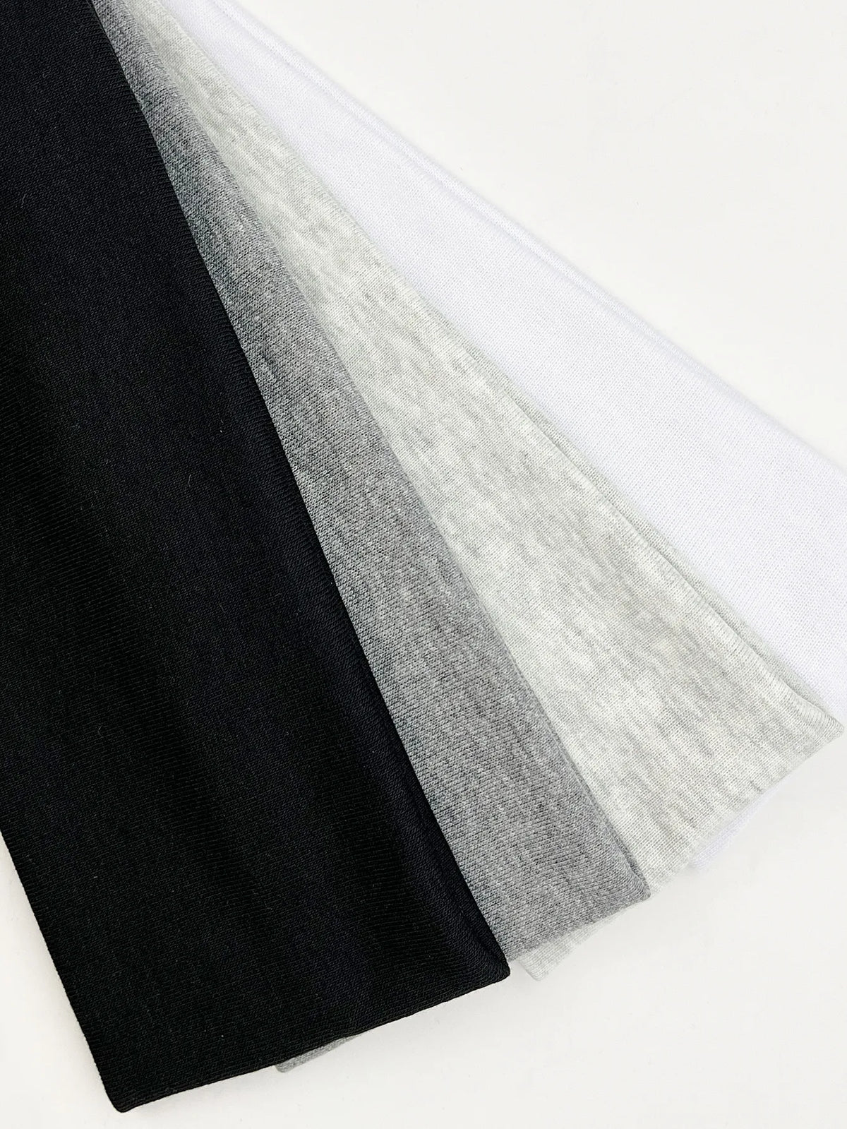 A stack of four knitted hair bands in black, gray, and white colors.