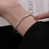 A close-up of a silver twisted wave cuff bracelet worn on a woman's wrist.
