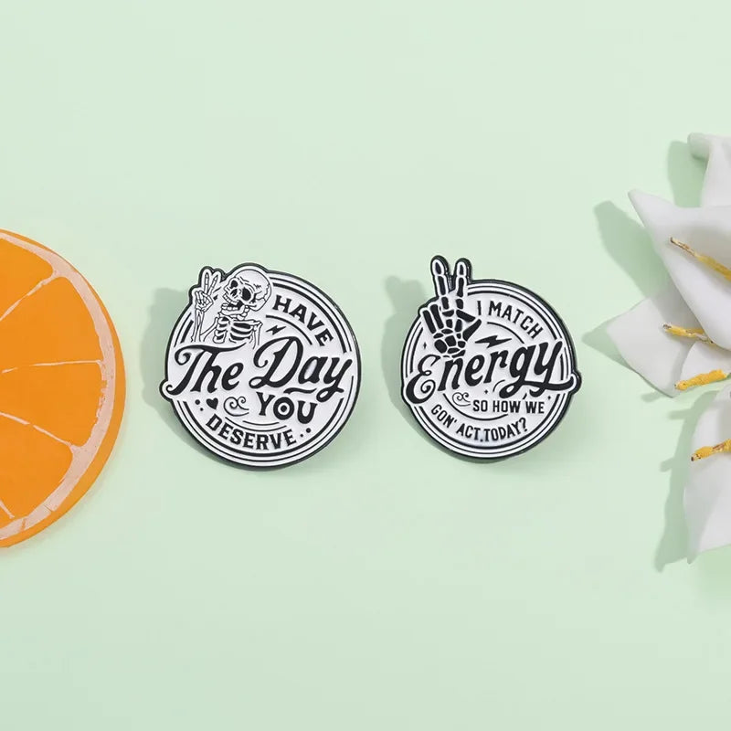 Three enamel lapel brooches featuring motivational text about having the day you deserve and matching energy.