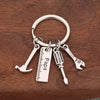 A silver multi-tool keychain set featuring a knife, screwdriver, and pliers resting on dark wood.