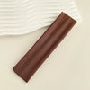 A dark brown fabric headband is laid diagonally on a light surface next to white wavy fabric.