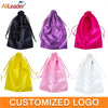 A collection of satin wig storage bags in black, purple, pink, yellow, and white with drawstrings.