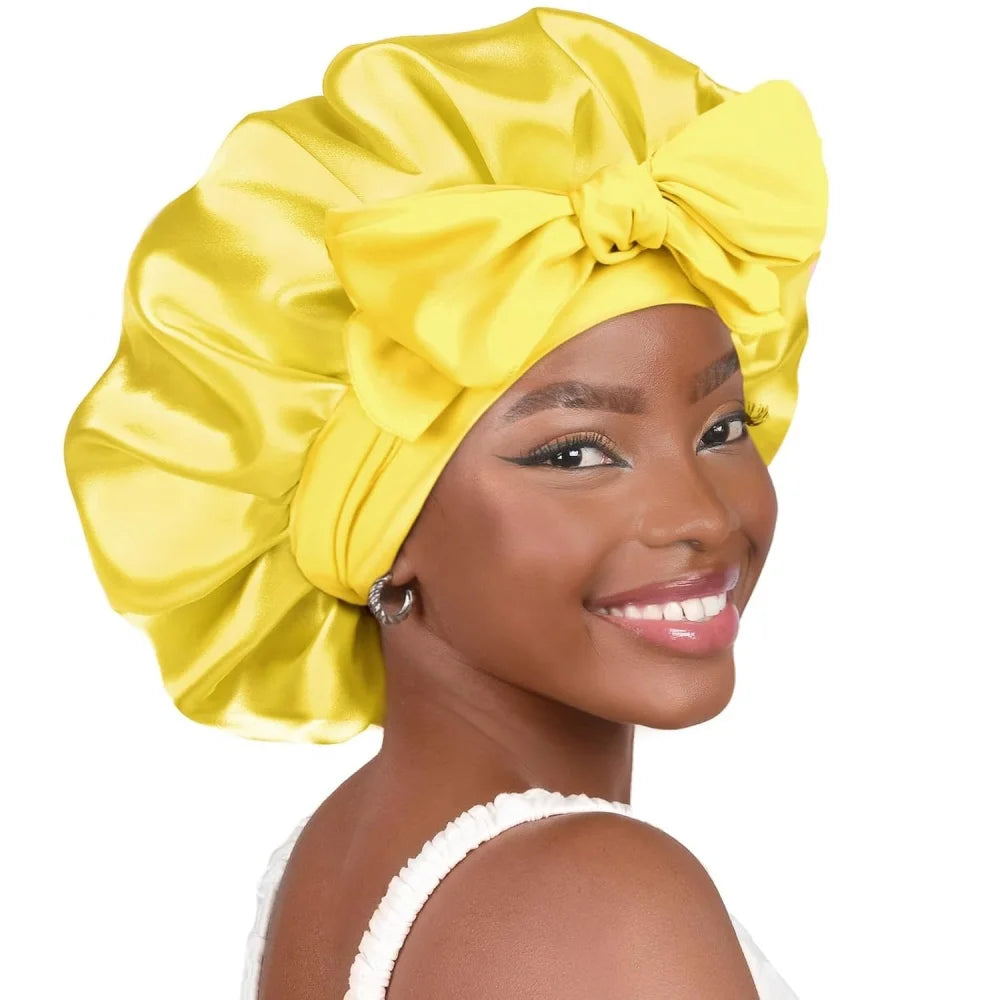 A woman is wearing a yellow satin sleeping bonnet tied in a large bow.