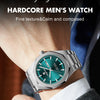 A close-up of a stainless steel watch with a teal face and silver bezel worn on a wrist.