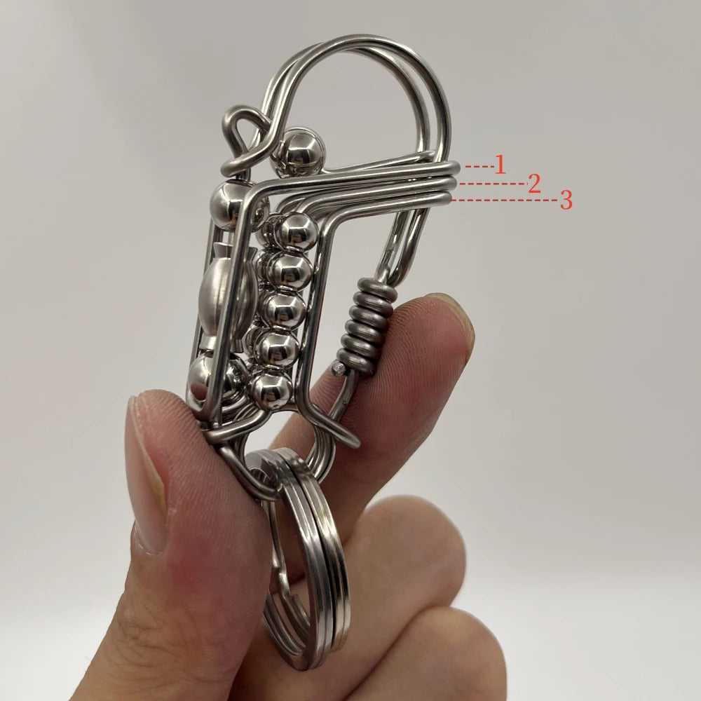 Un porte-clés mécanique en acier inoxydable avec anneau divisé et éléments décoratifs, tenu dans une main.