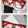 A pair of bright red, retro cat-eye sunglasses resting on a white surface.