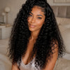 A woman with long, dark, curly hair is looking at the camera in a soft indoor setting.