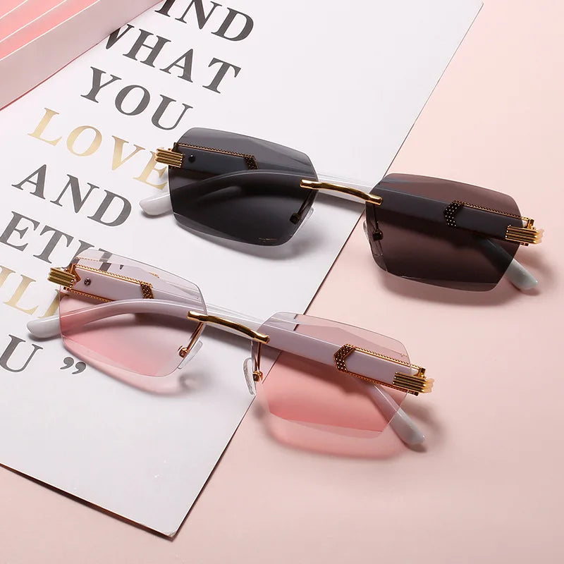 A pair of frameless gradient sunglasses with brown and pink lenses resting on a white paper background.