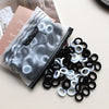 A pile of black and white elastic hair bands is shown next to a packaged product featuring a cat design.