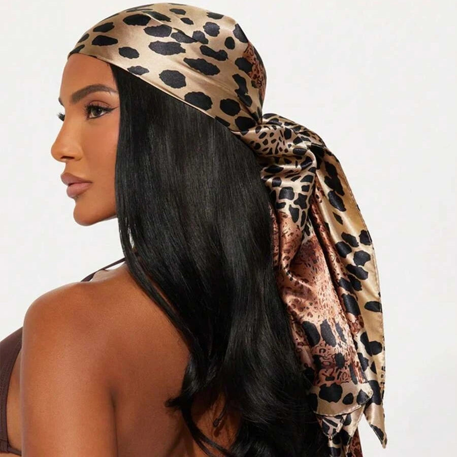 A woman models a leopard print square satin scarf draped over her head and hair.